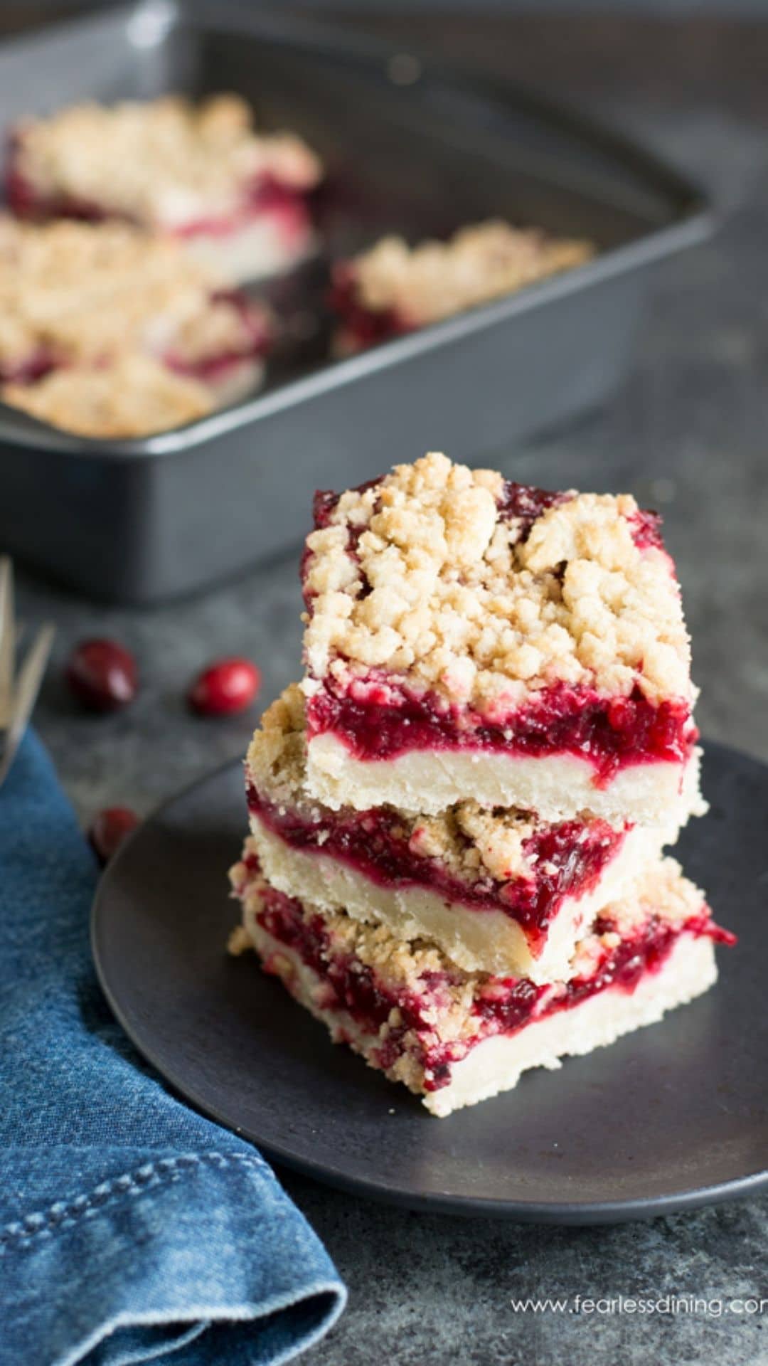 Three gluten free cranberry shortbread bars stacked on a small black plate.