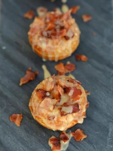 two maple bacon donuts on a slate serving dish