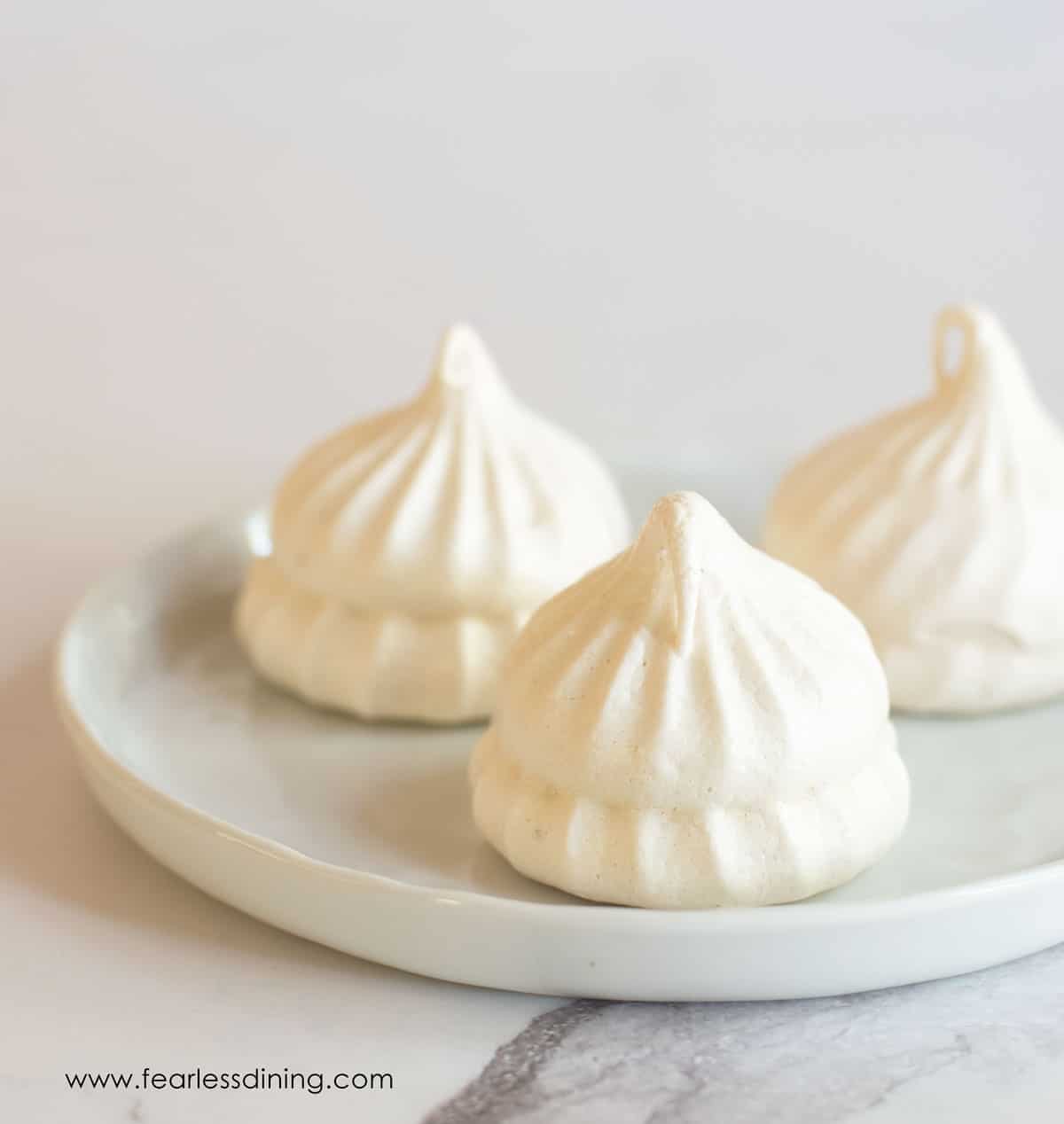 Three meringue cookies on a small white plate.