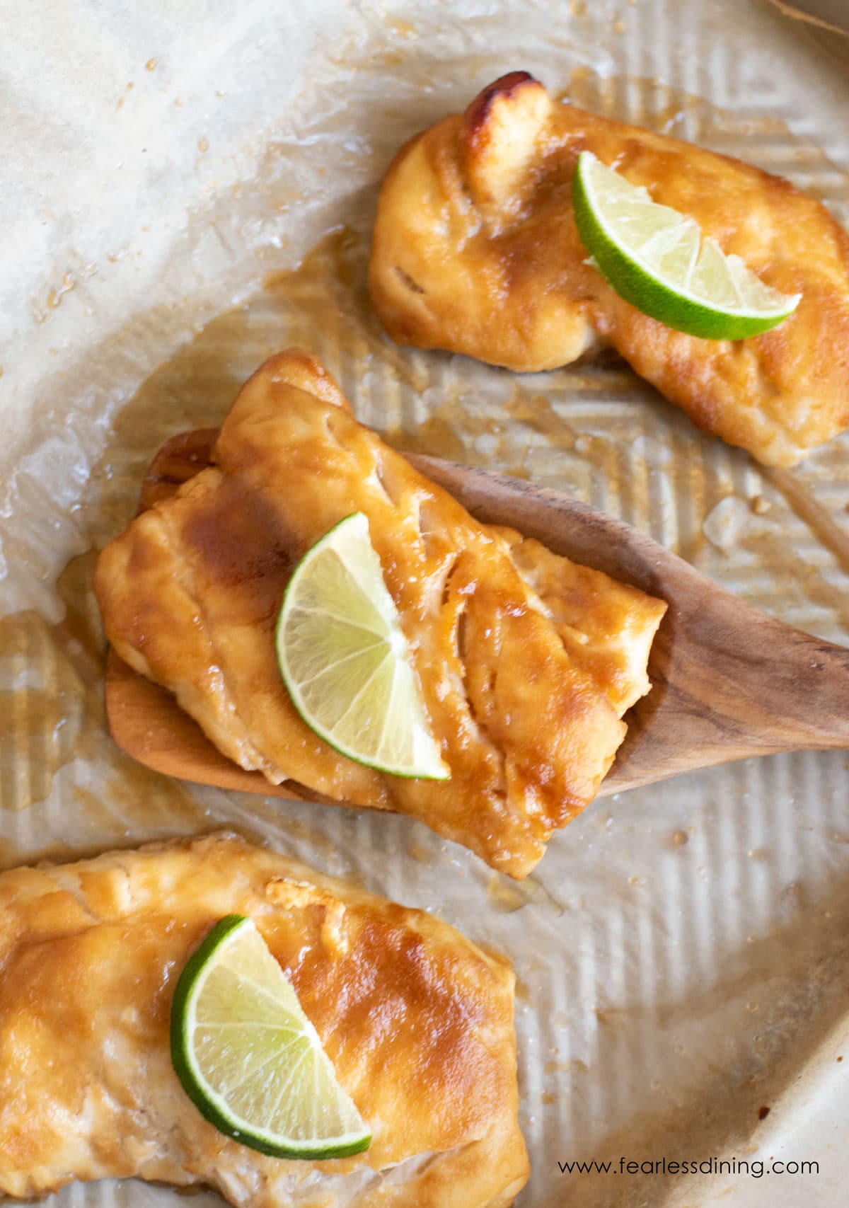 Baked pieces of miso glazed cod on a wooden serving spoon.