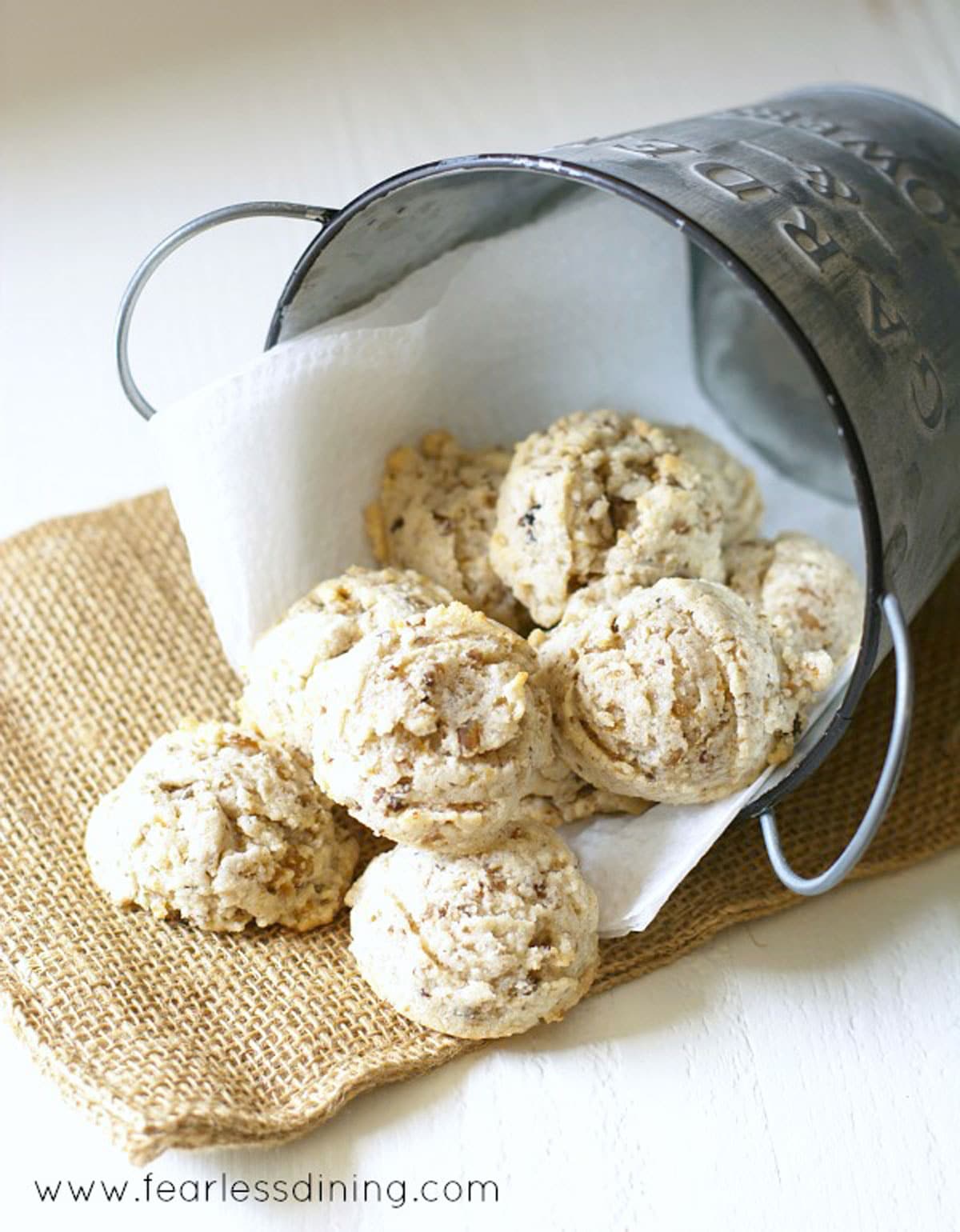 A small silver pail tipped on its side, filled with roasted chestnut cookies.