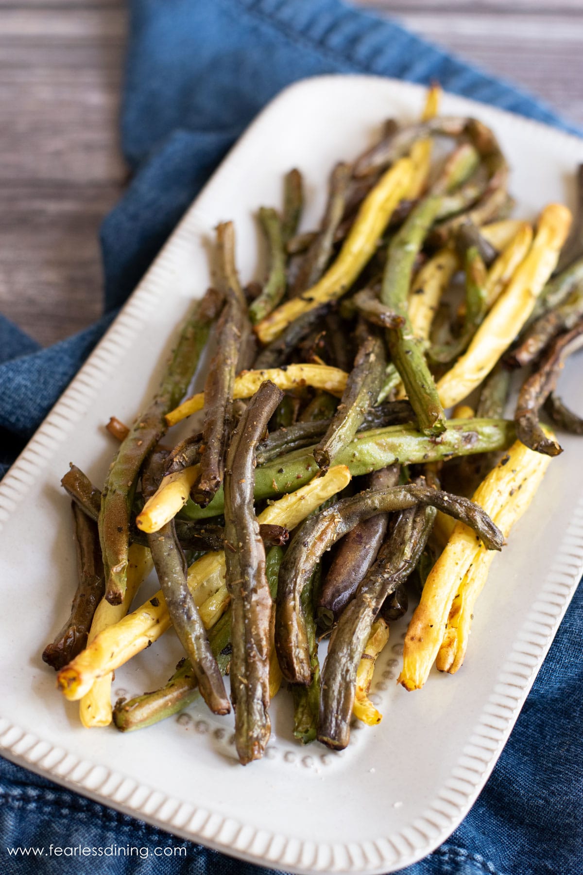 The top view of a white platter filled with air fried green beans.