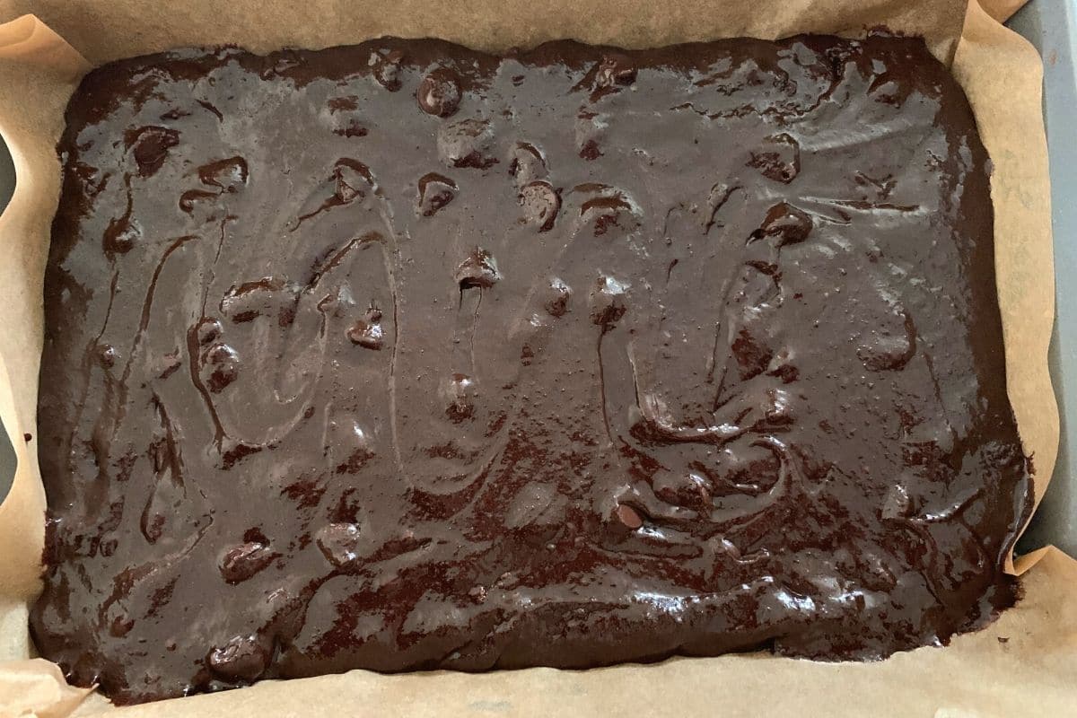 Brownie batter spread out in a pan, ready to bake.