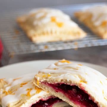 A gluten free cranberry hand pie cut in half on a white plate.