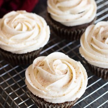 Frosted gingerbread cupcakes on a rack.