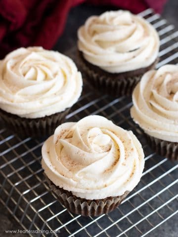 Frosted gingerbread cupcakes on a rack.