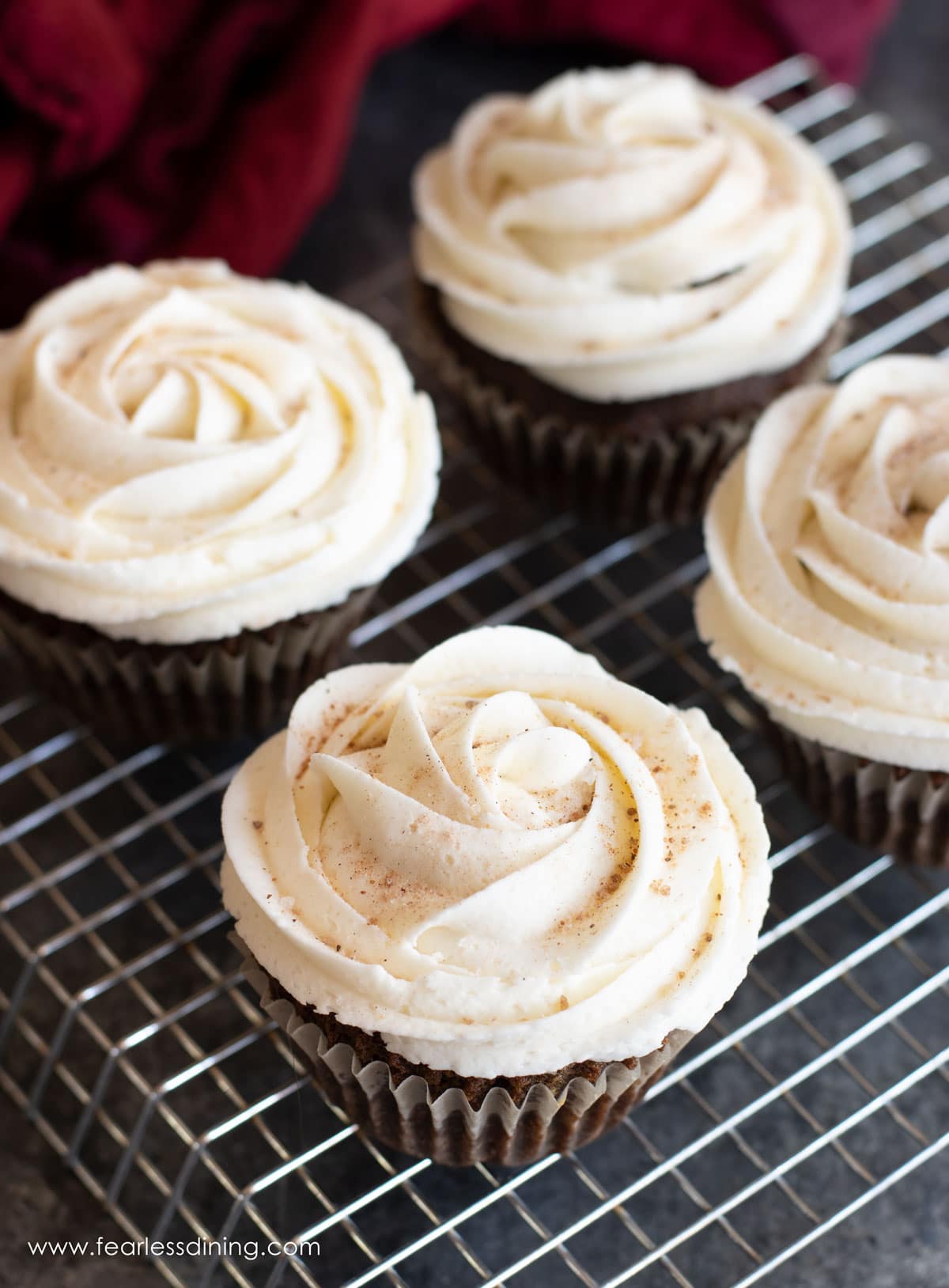 Frosted gluten free gingerbread cupcakes on a rack.