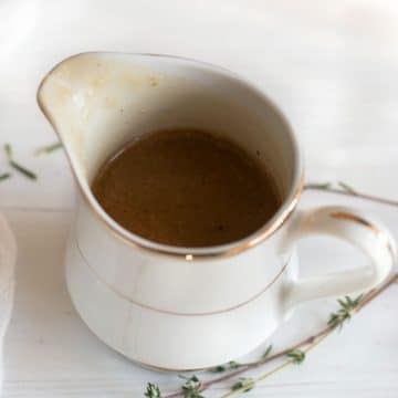A fancy white and gold China gravy boat filled with gluten free gravy.