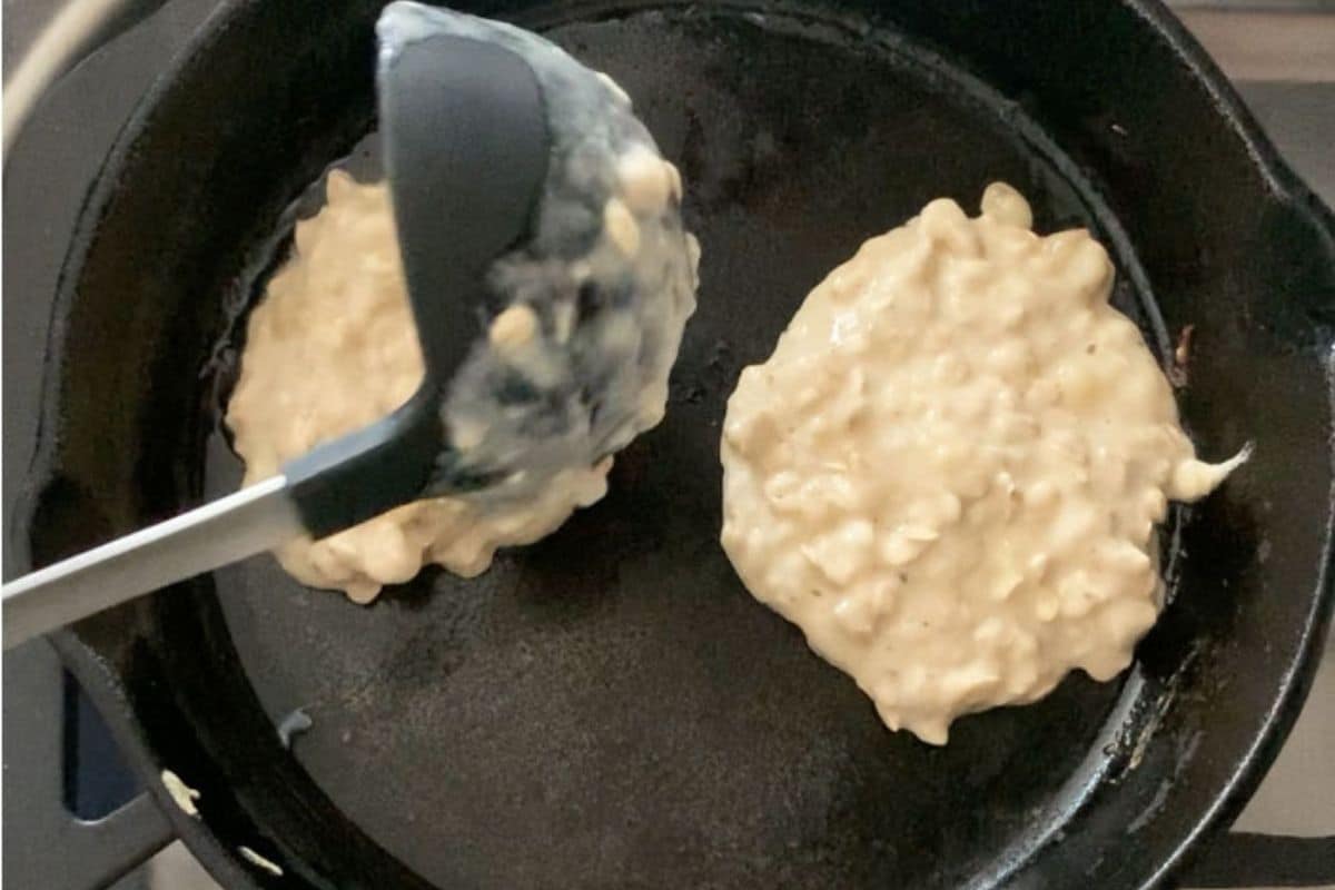 Adding oat pancake batter to a cast iron skillet.
