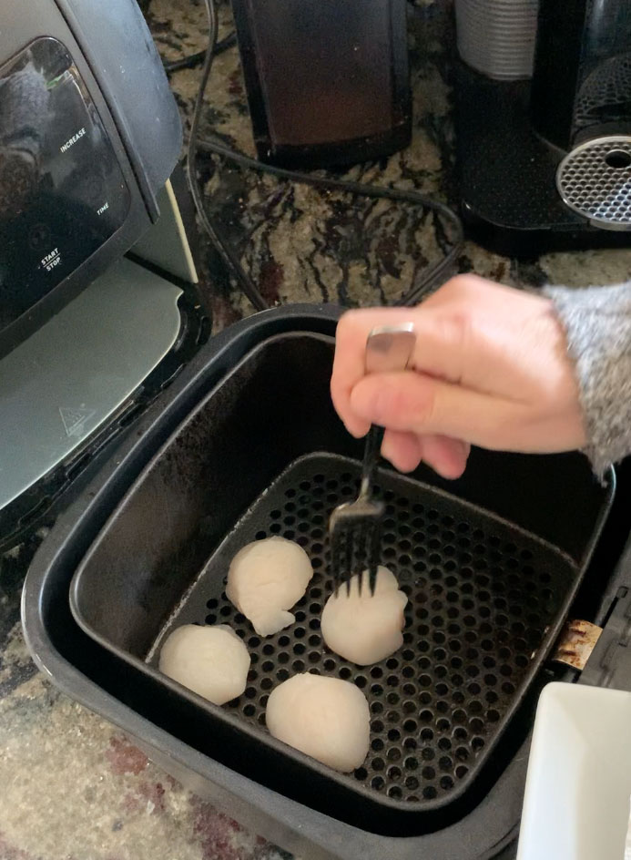 Putting the raw scallops into the air fryer.