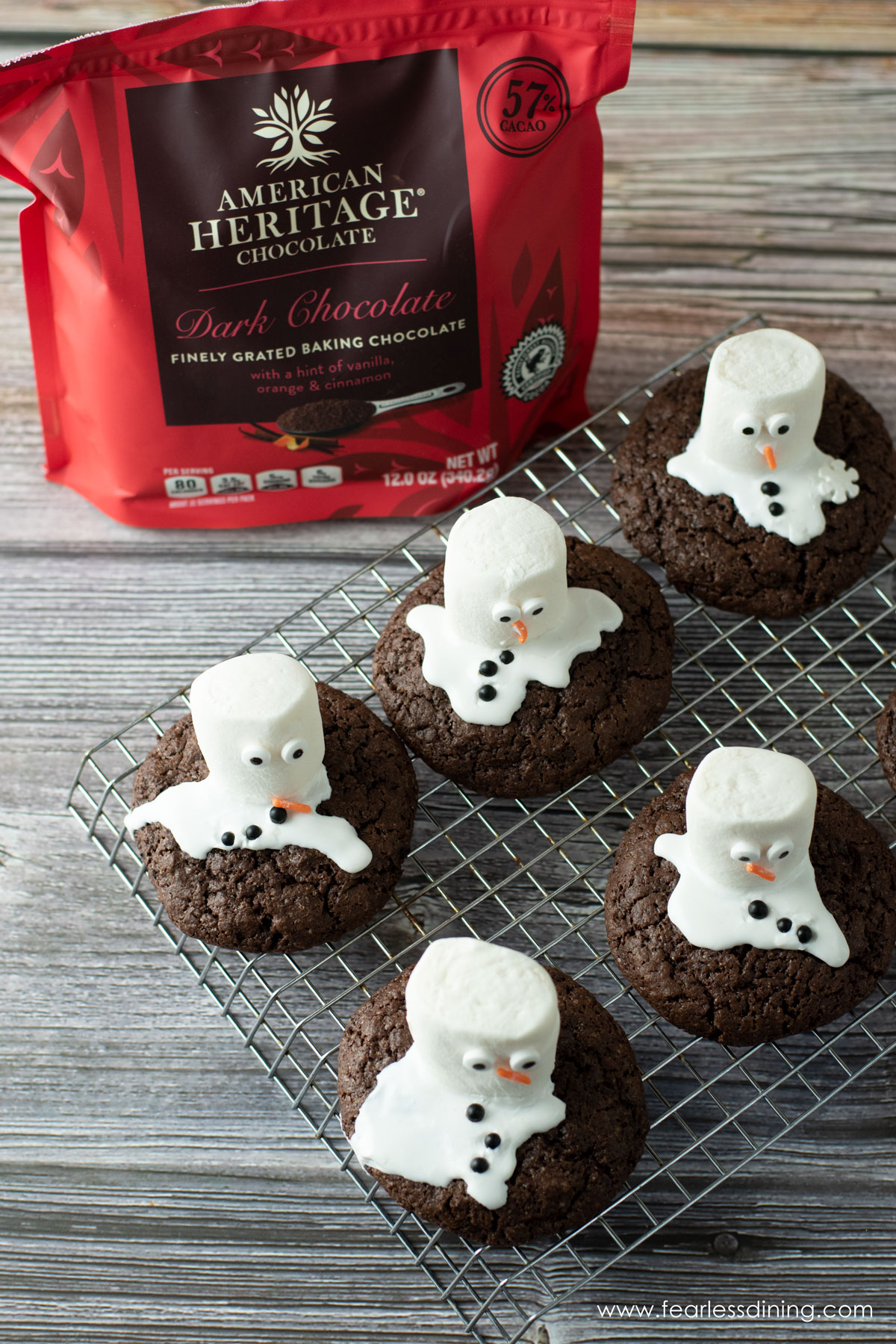 Melted snowman cookies on a rack next to a bag of chocolate shavings.