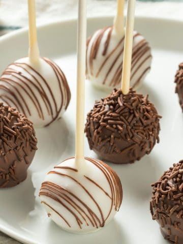 A plate with white chocolate and milk chocolate coated cake pops.