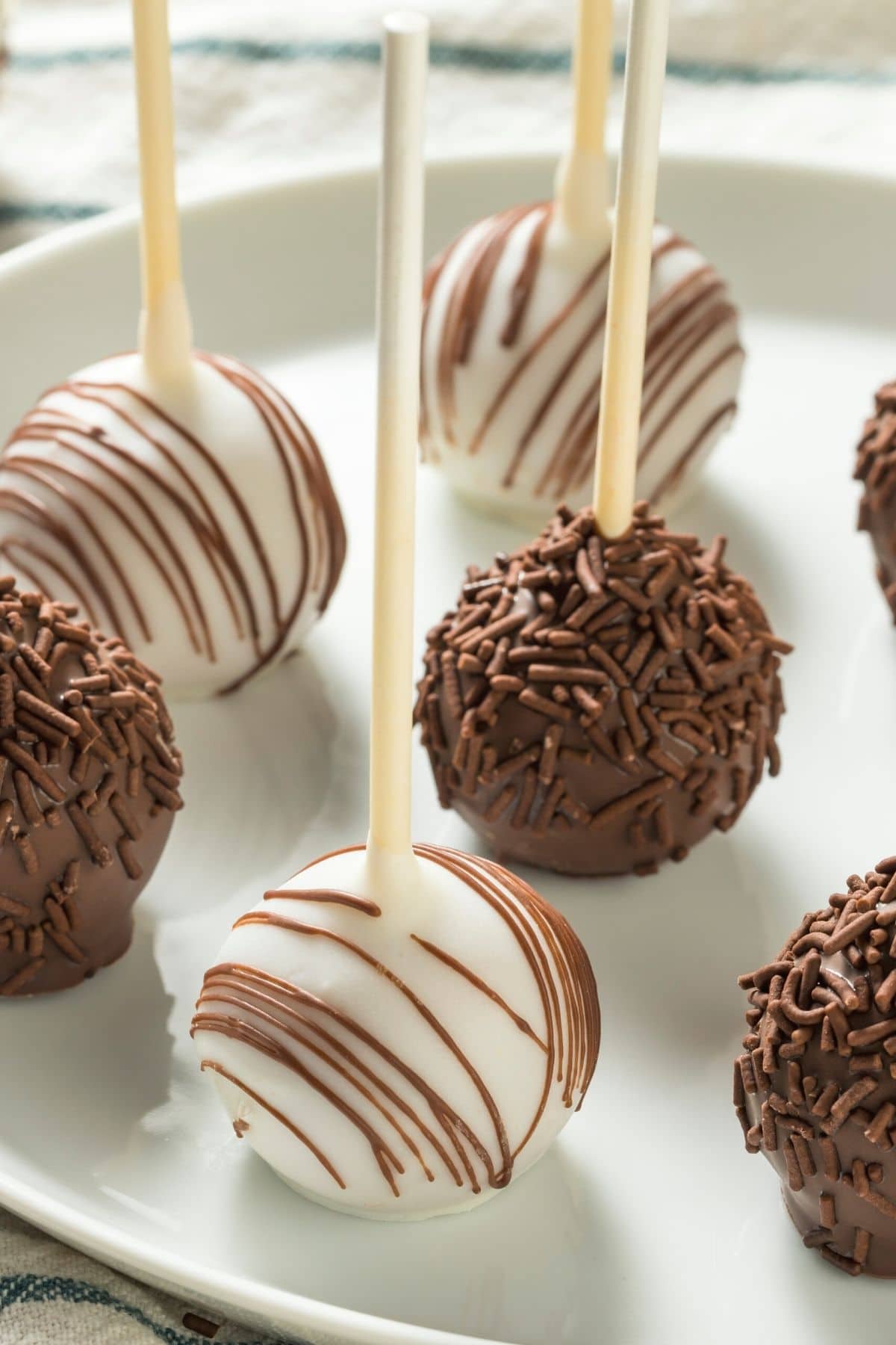A plate with white chocolate and milk chocolate coated cake pops.