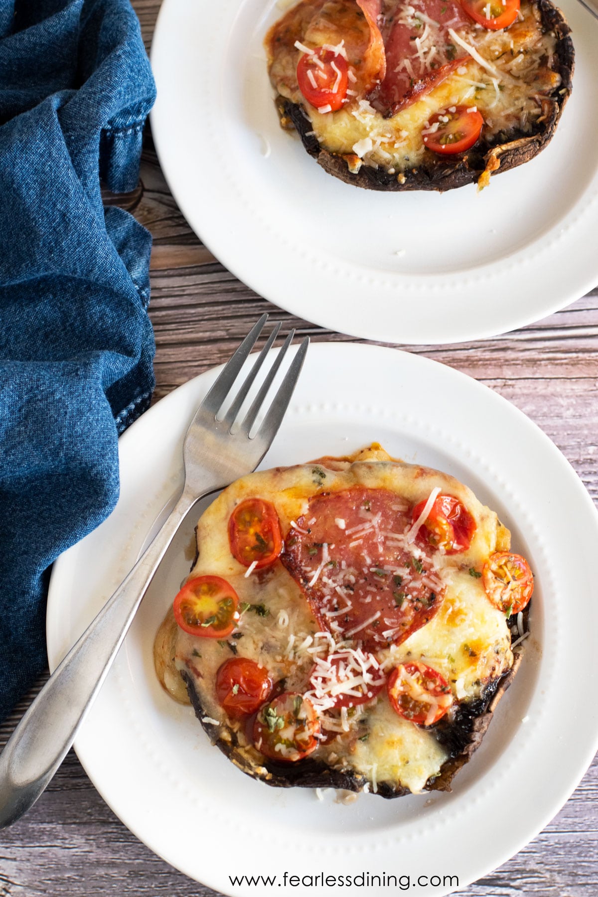 The top view of two portobello pizzas on small white plates.