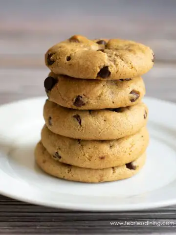 A stack of five gluten free caramel stuffed chocolate chip cookies on a white plate
