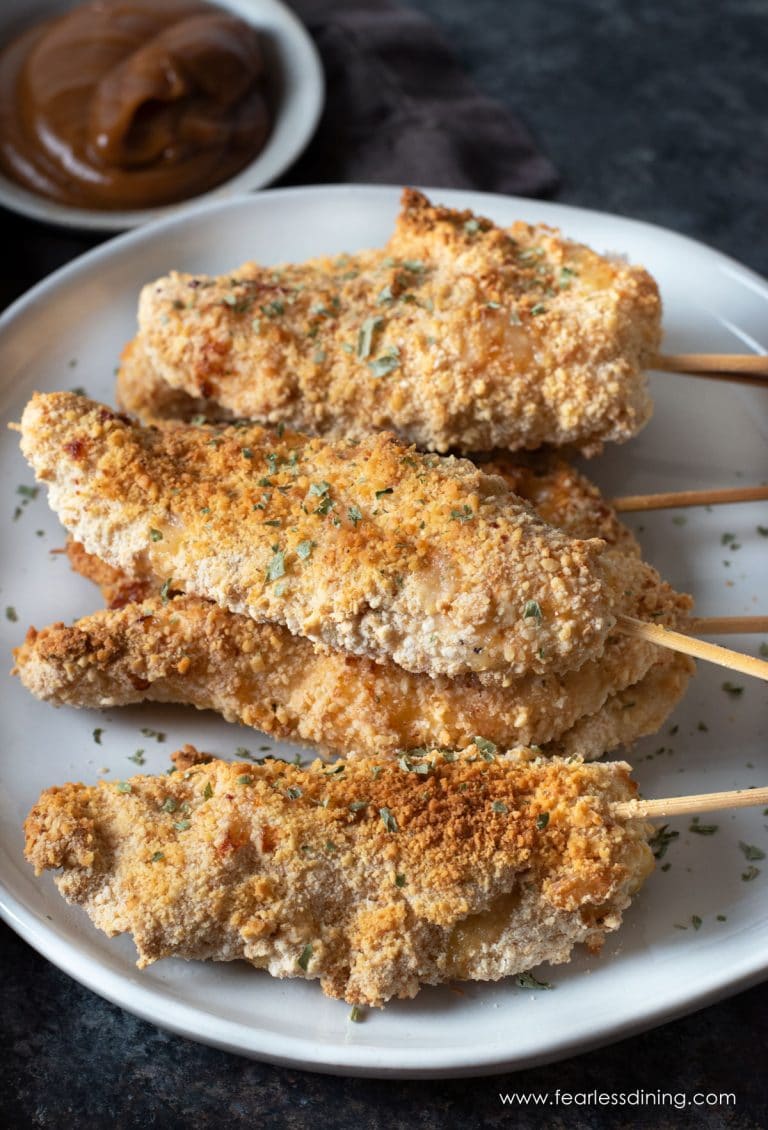 A white plate with several gluten free breaded chicken tenders on it.