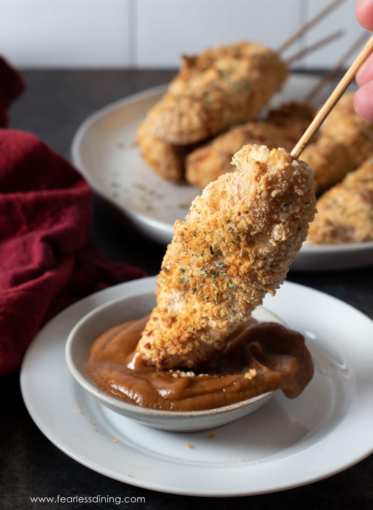 dipping a chicken satay in peanut sauce