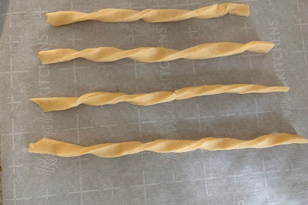 Photos of the cheese straws twisted on a baking sheet.