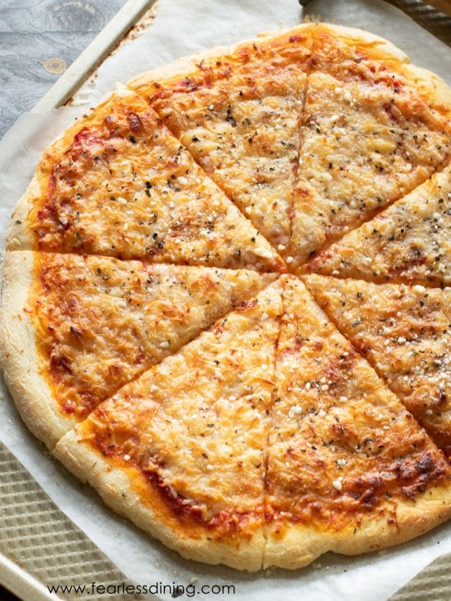 A top view of a sliced baked pizza on a baking pan.