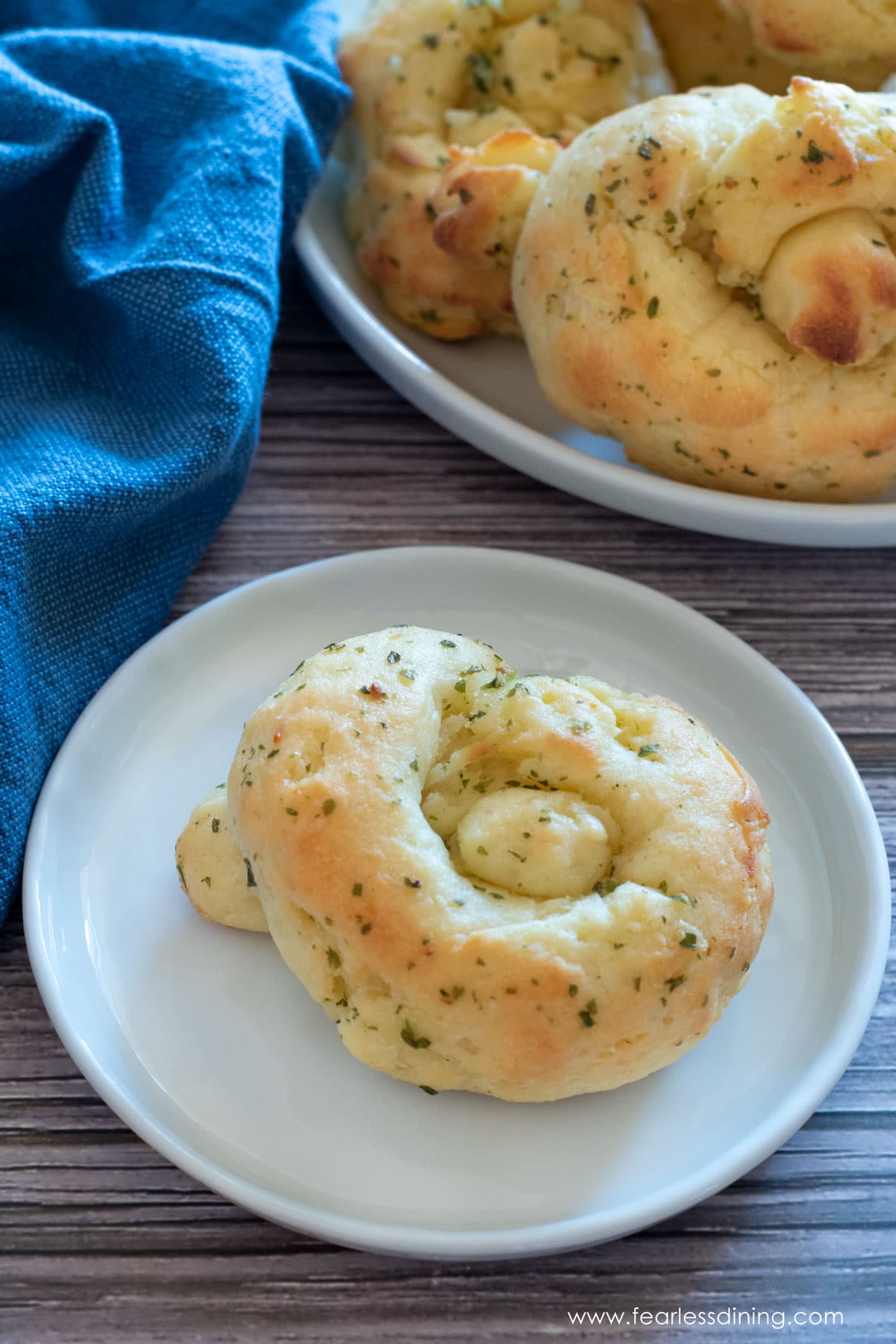 A buttery gluten free garlic knot on a white plate.