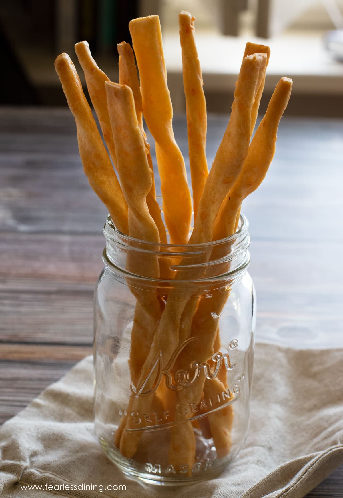 A jar filled with crispy gluten free cheese straws.