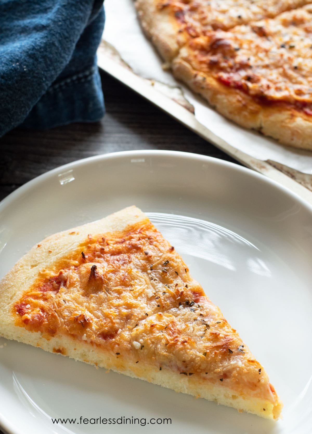 A slice of gluten free pizza on a white plate.