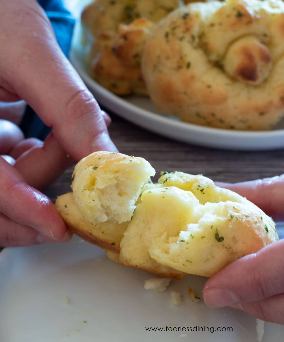 Hands tearing open a garlic knot.