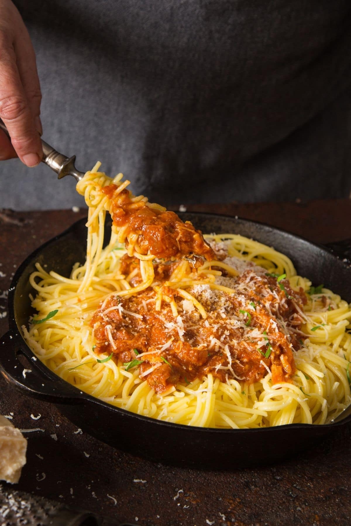 Stirring ground pork pasta sauce into spaghetti.
