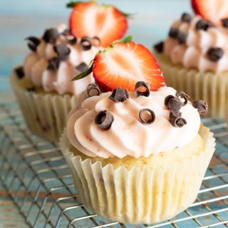 Frosted gluten free strawberry cupcakes on a rack.