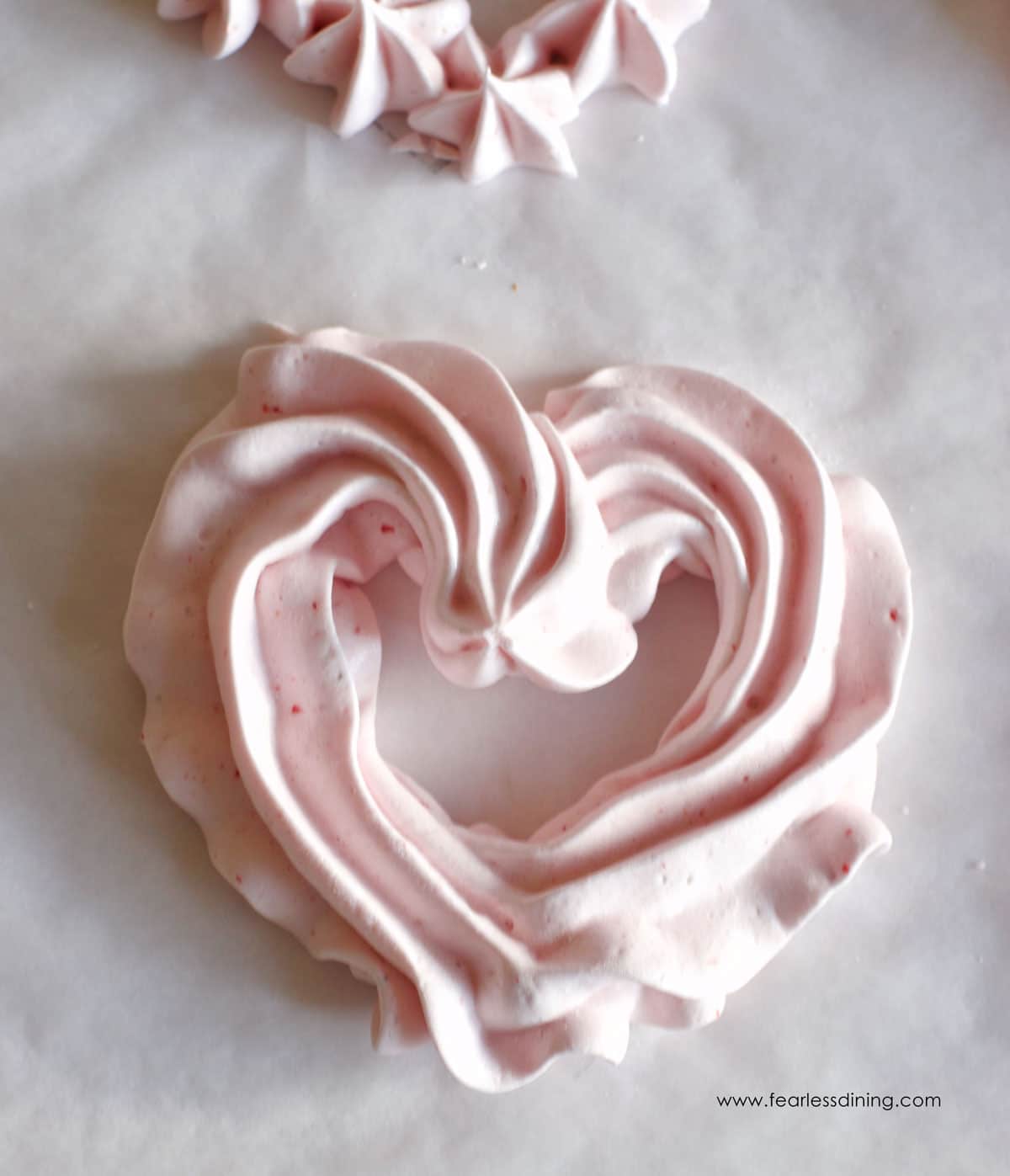 A baked heart shaped meringue cookie on a tray.