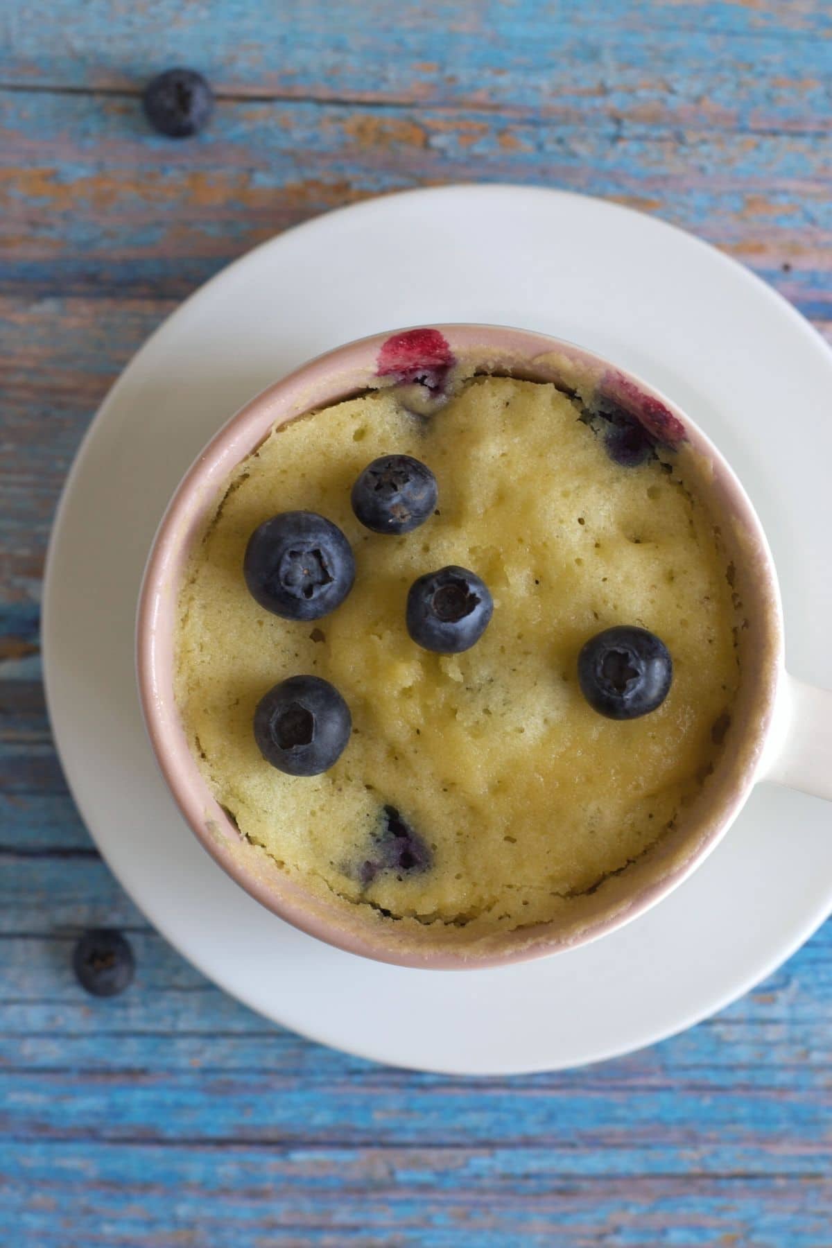 The top view of the cooked blueberry muffin in the mug.