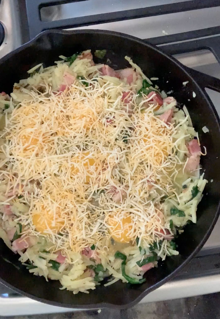 Adding a layer of cheese to the skillet.