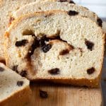 A sliced loaf of gluten free cinnamon raisin bread on a cutting board.