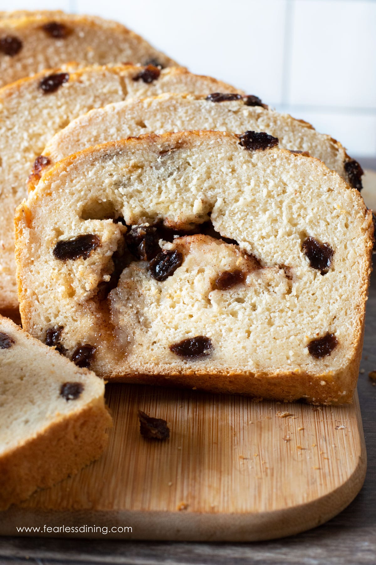 A sliced loaf of gluten free cinnamon raisin bread on a cutting board.