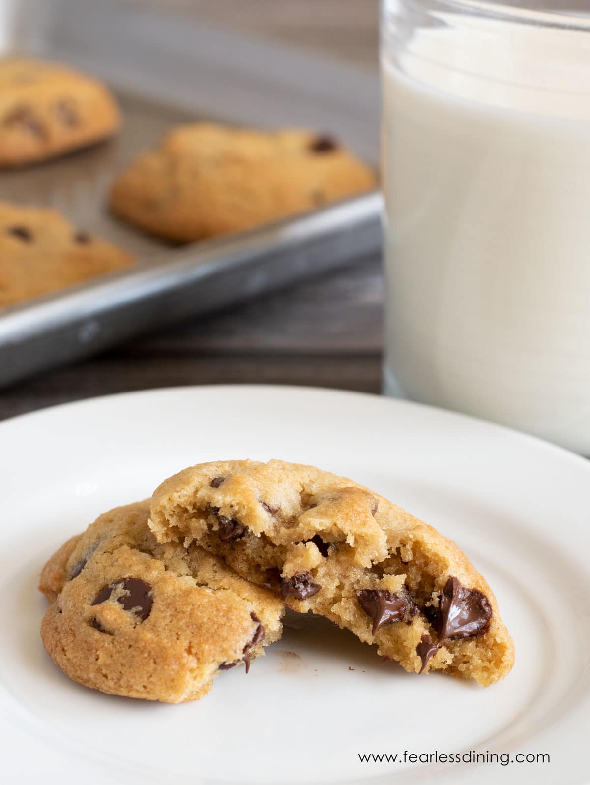 A Toll House cookie broken in half on a plate.