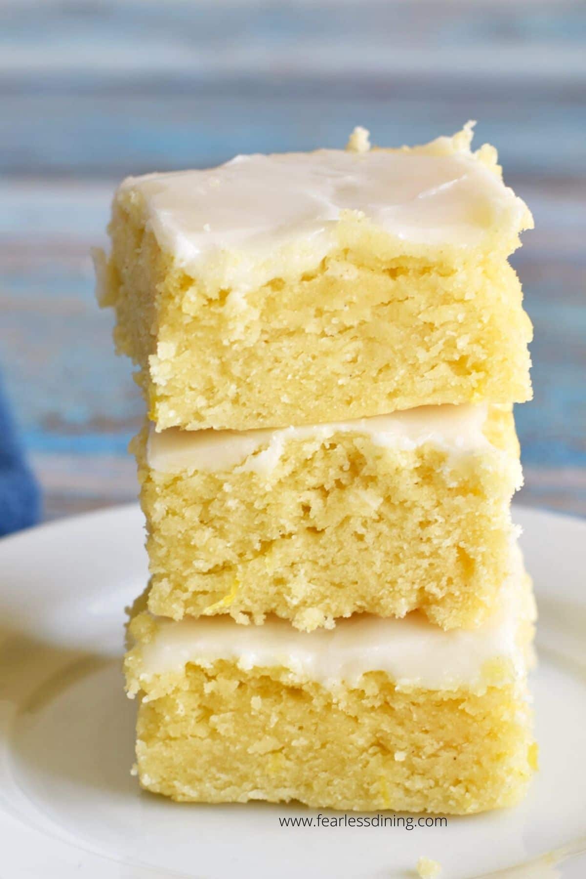 Three lemon brownies stacked on top of each other on a plate.