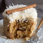 A gluten free carrot mug cake with a slice taken out. It is frosted.