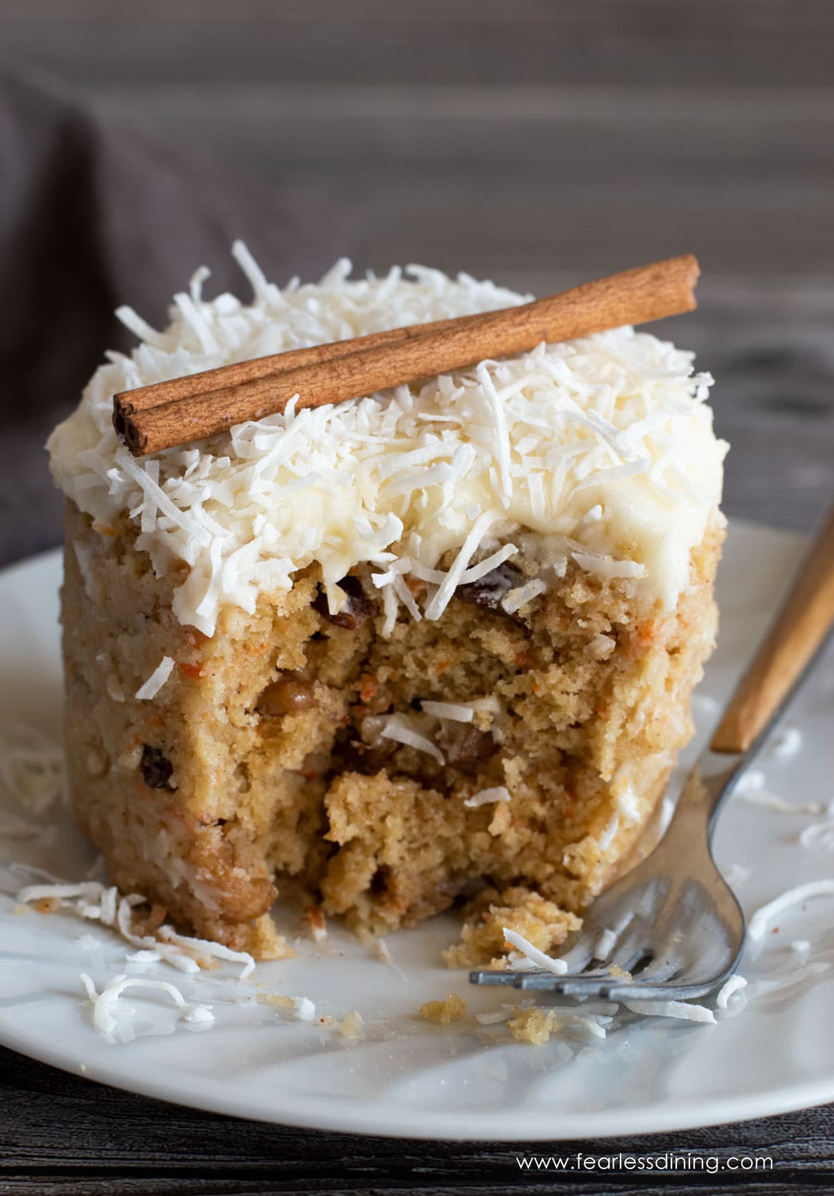 A gluten free carrot mug cake with a slice taken out. It is frosted.