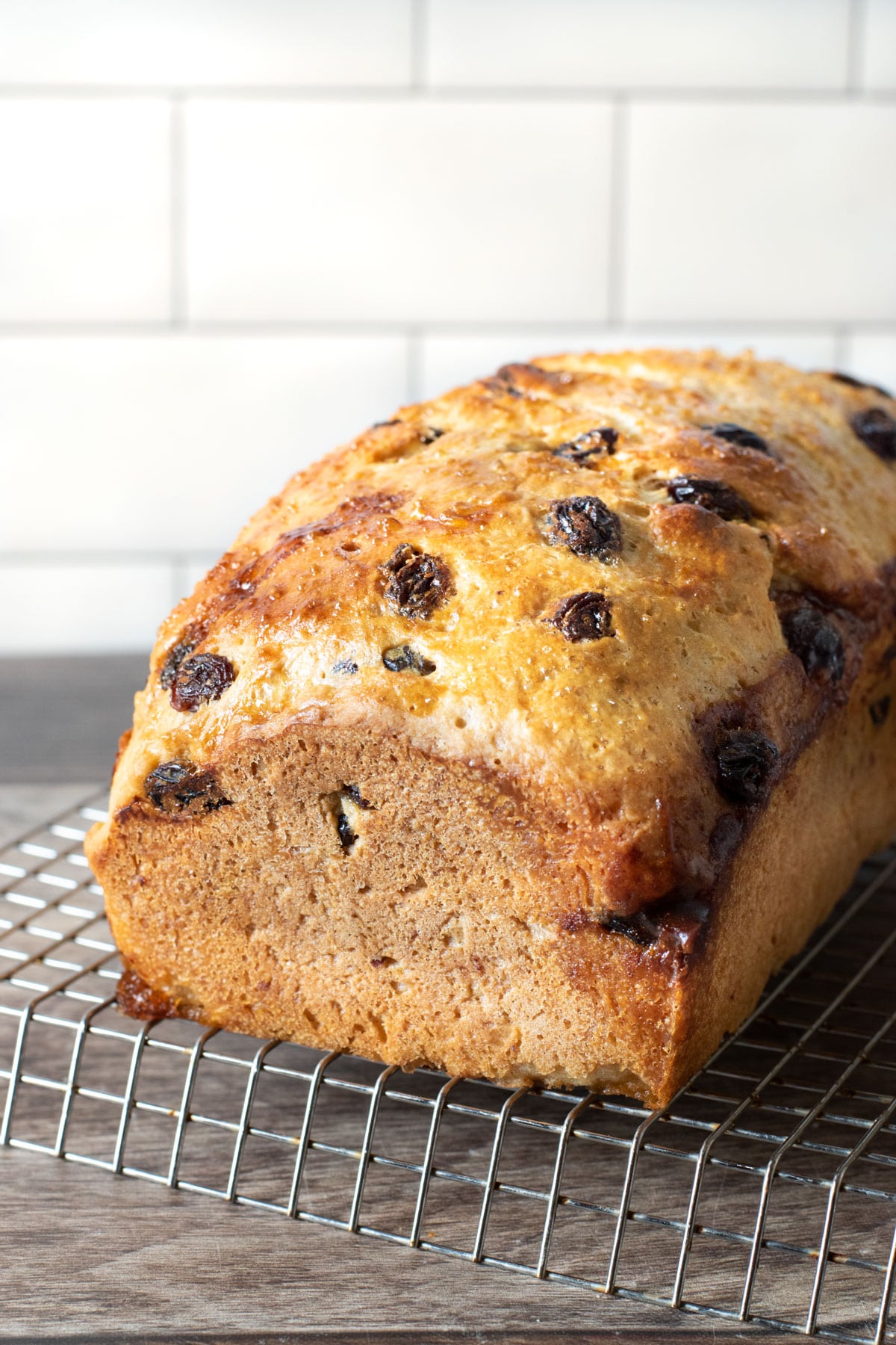 A loaf of baked cinnamon raisin bread on a rack.