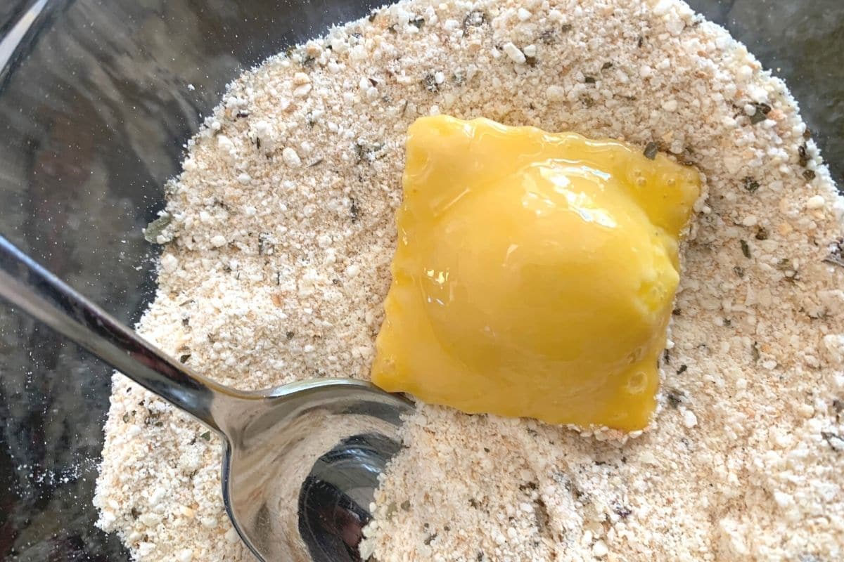 Dipping the egg coated ravioli in bread crumbs.