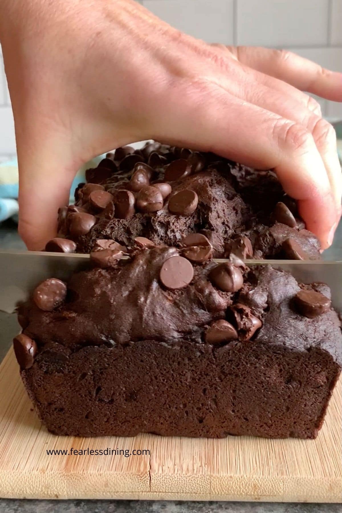 Slicing the chocolate banana bread on a cutting board.