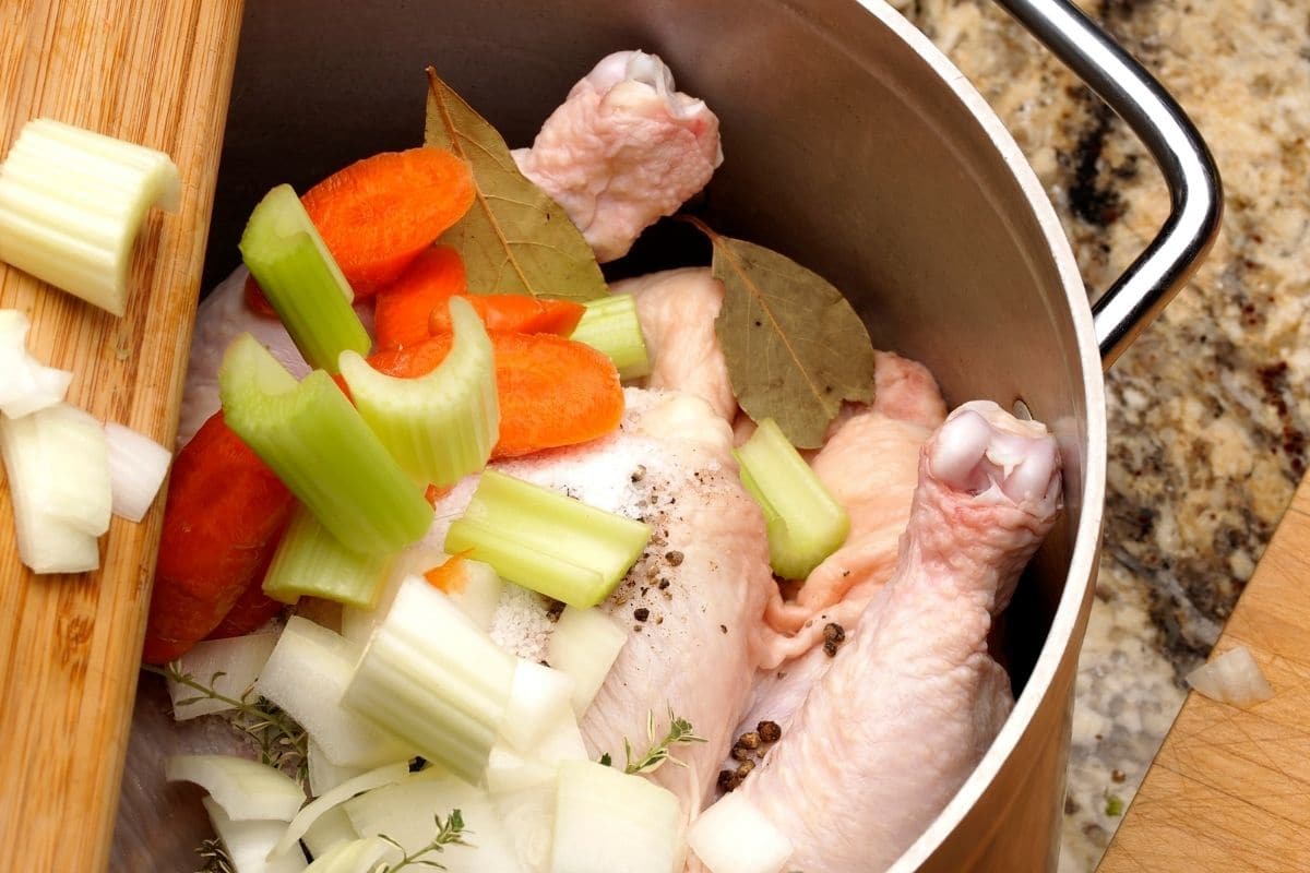 Adding chicken soup ingredients to a pot.