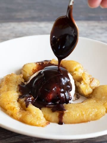 drizzling hot fudge over caramelized air fryer bananas and ice cream.