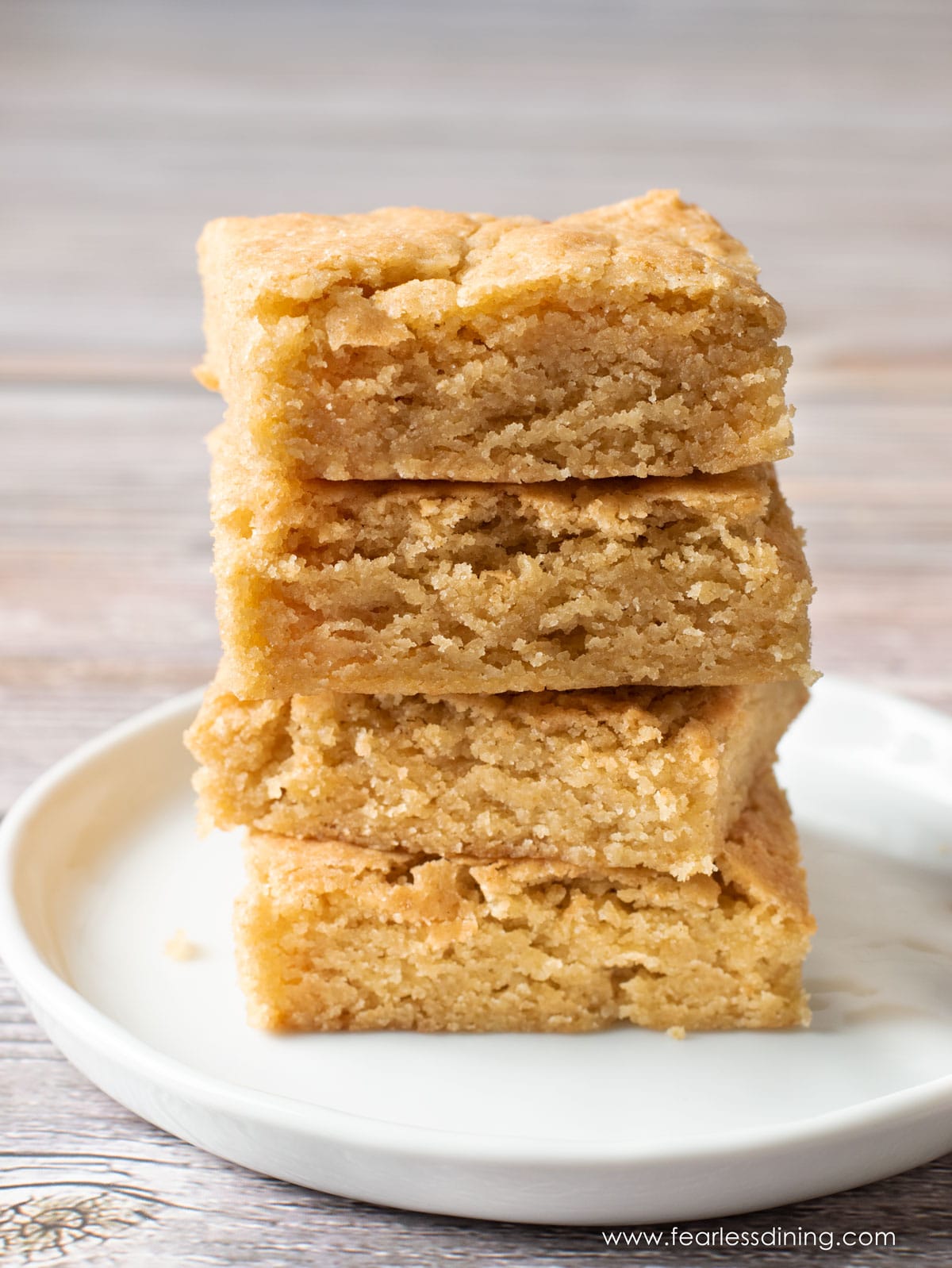 A stack of four gluten free butterscotch brownies on a plate.