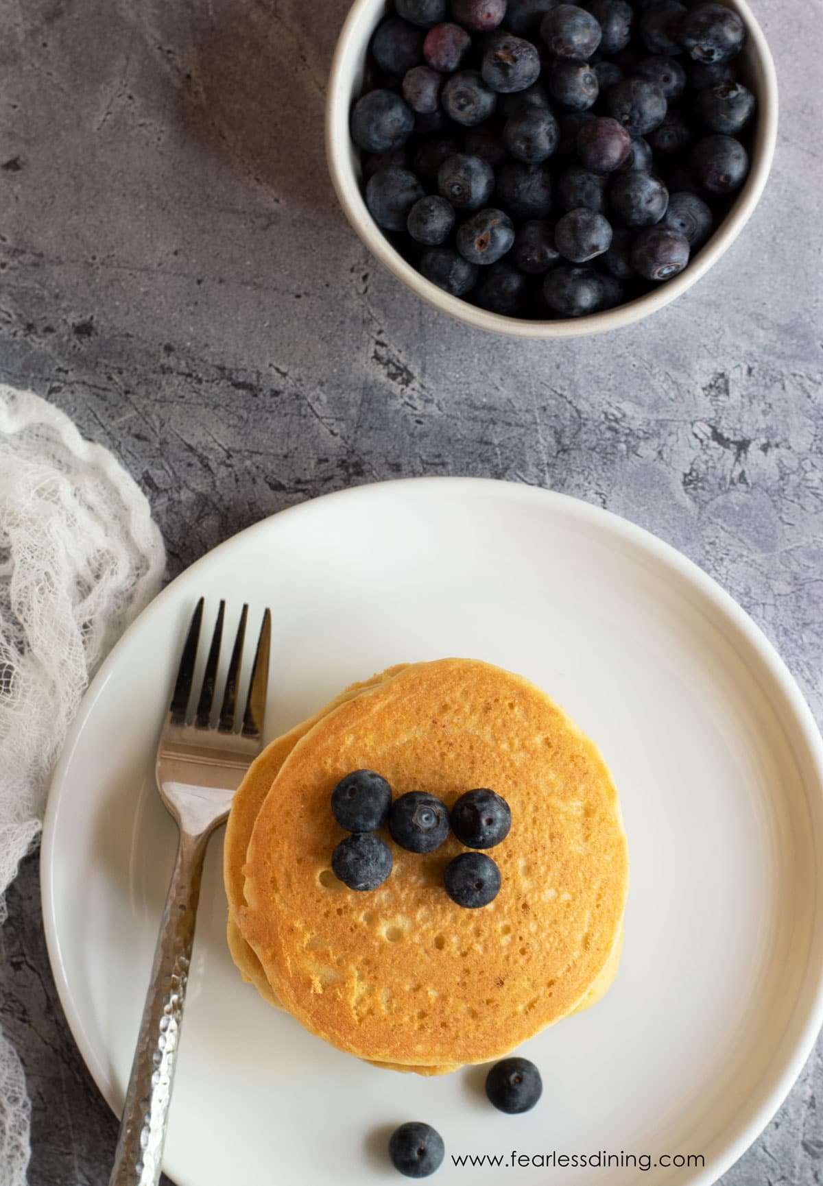 The top view of a stack of pancakes with fresh blueberries.