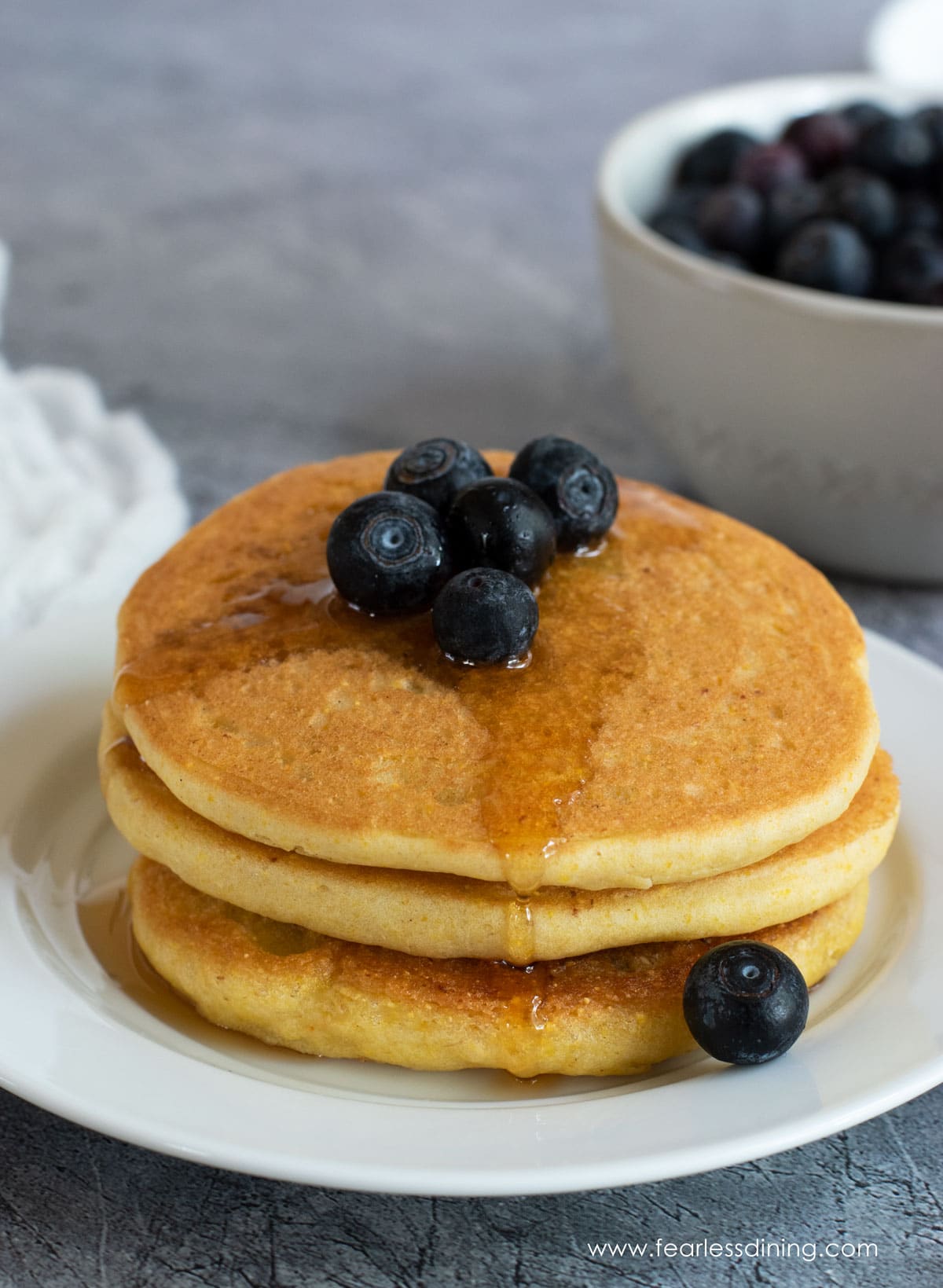 Gluten free cornmeal pancakes stack with syrup.