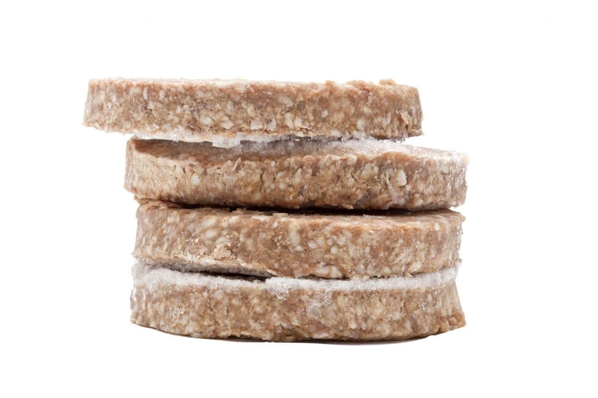 Four frozen burger patties stacked up.