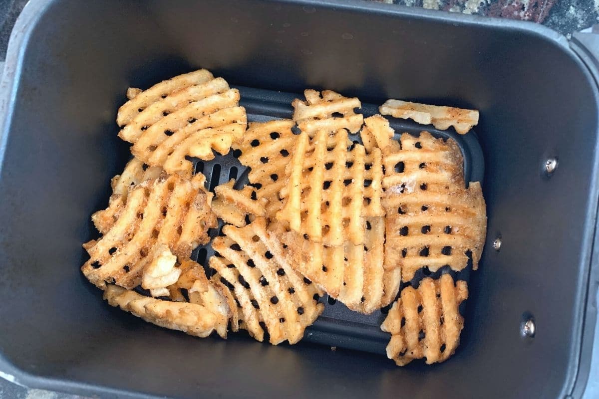 Frozen waffle fries in the air fryer basket.