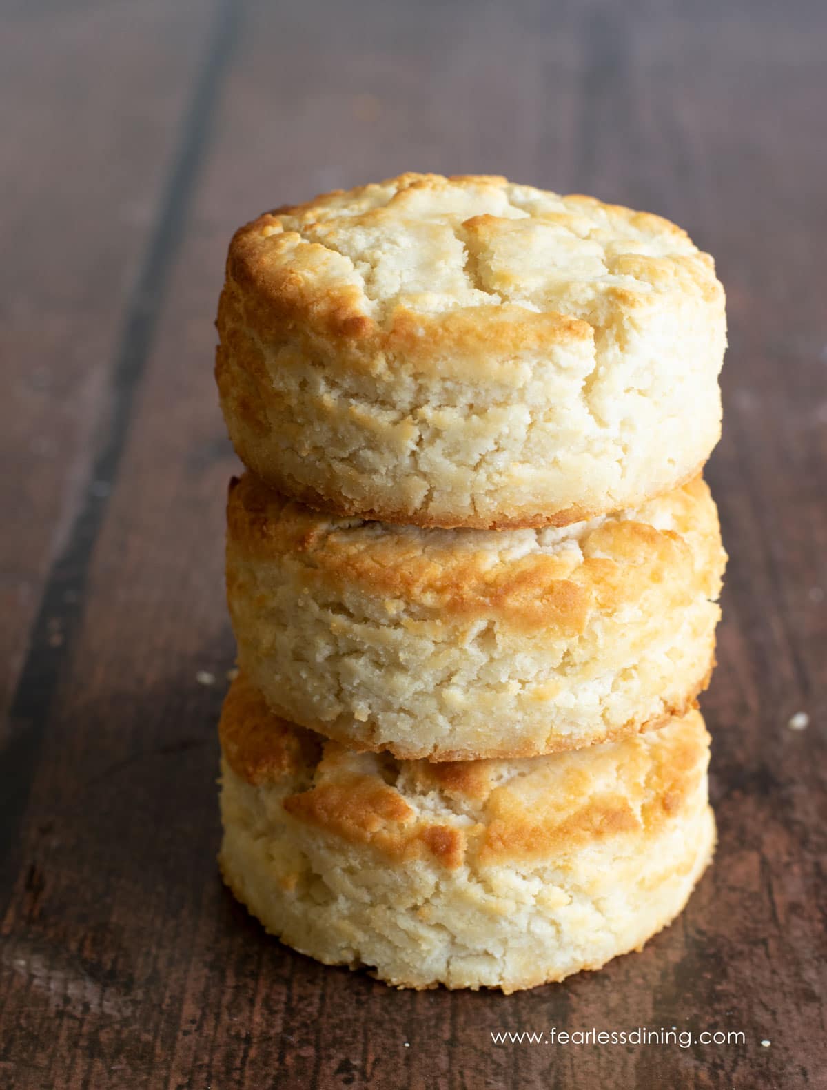 A stack of three gluten free bisquick biscuits on a wooden table.