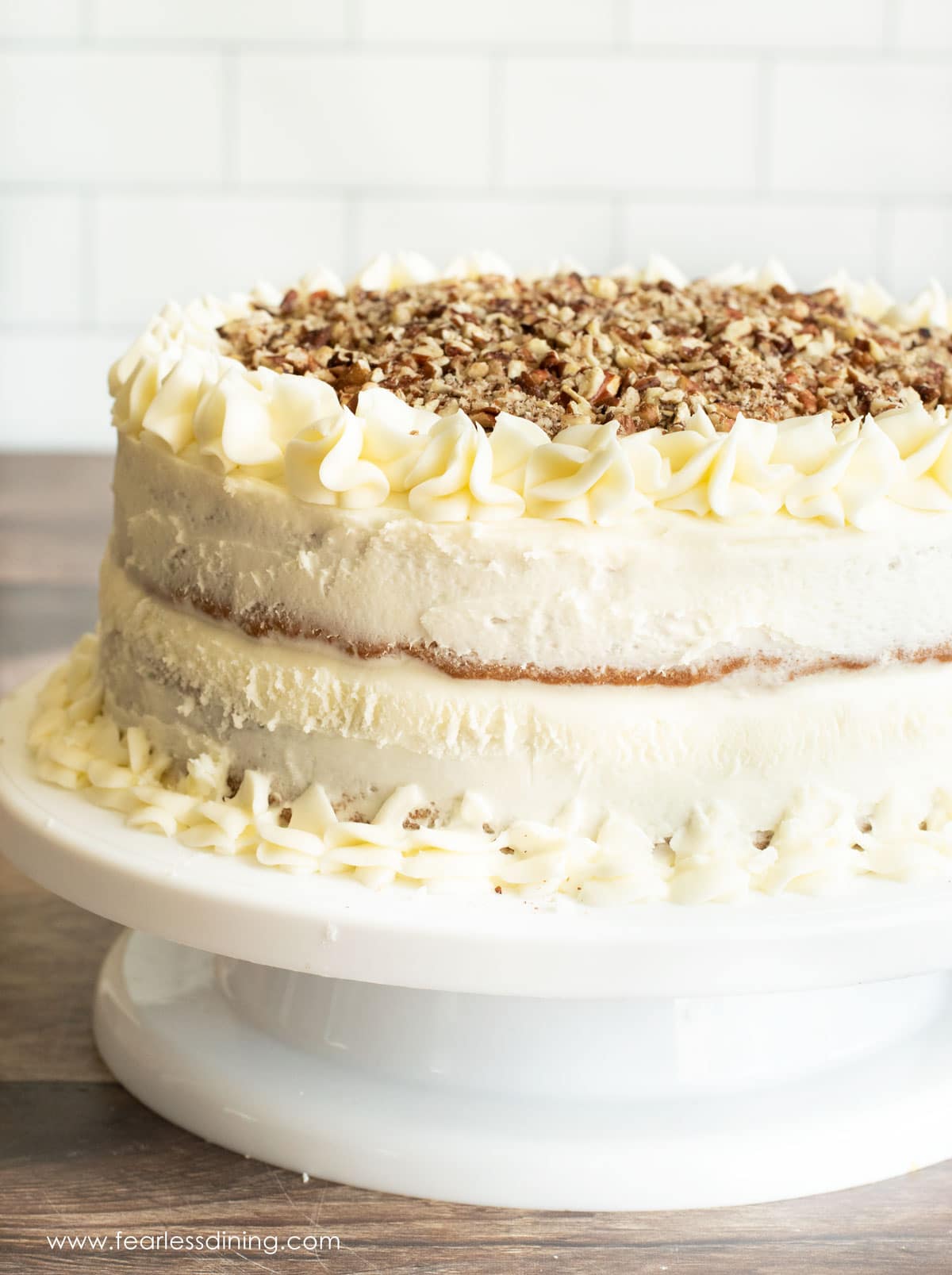 A frosted hummingbird cake on a white cake stand.